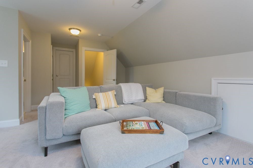 Sloped ceiling room featuring light-toned carpeting and flush-mounted ceiling lighting