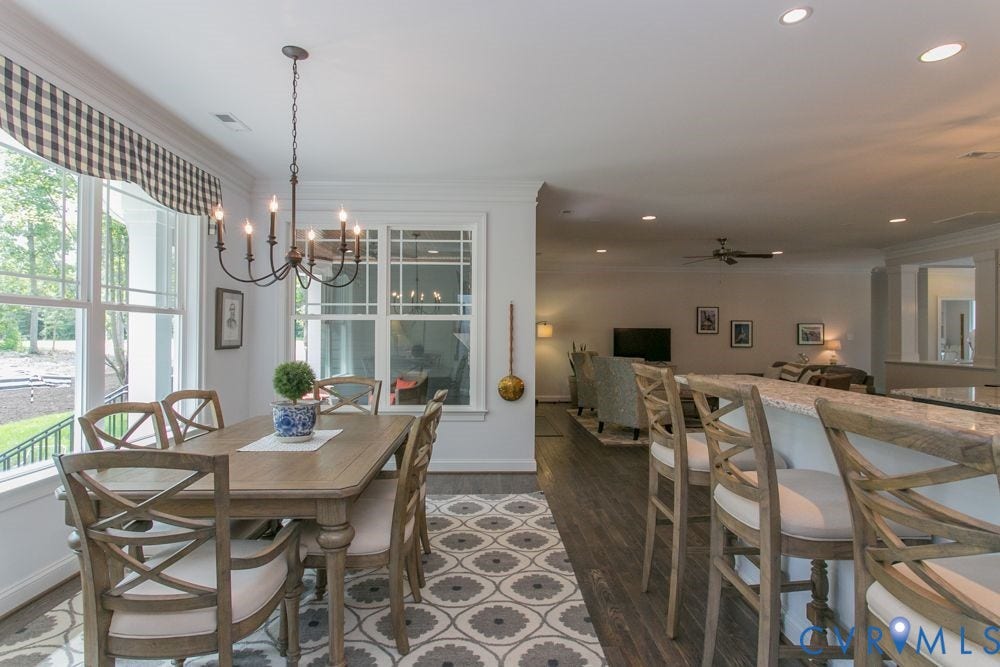 Dedicated dining area with large windows, an overhead chandelier, and wood-finish flooring