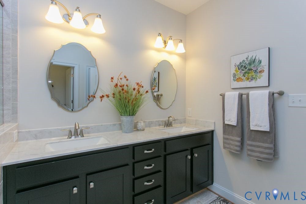 Dual vanity with dark cabinetry and brushed nickel hardware, undermount sinks, and light-toned countertops