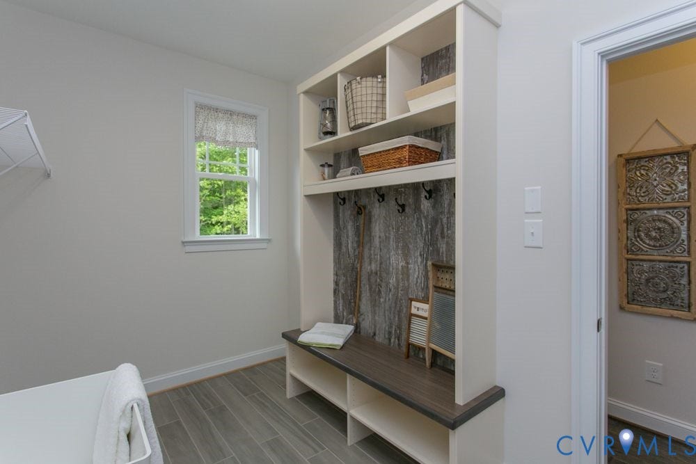 Built-in storage bench with open shelving, integrated coat hooks, and a distressed wood-finish back panel