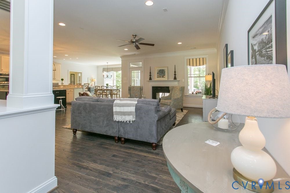 Open-concept living space featuring wood-finish flooring, recessed lighting, a ceiling fan, and a fireplace with a mantel