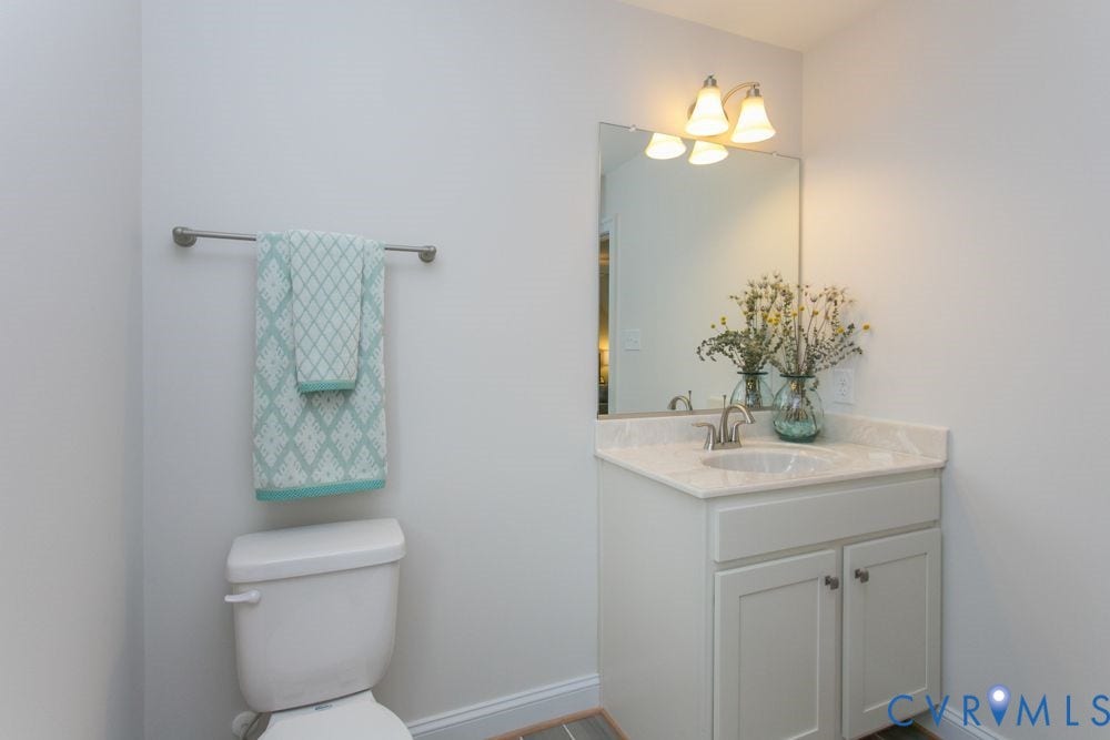 White vanity with double cabinet doors, a rectangular undermount sink, and a countertop
