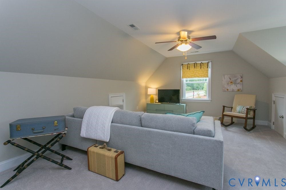Sloped ceilings, recessed window, ceiling fan with integrated lighting, and neutral carpeting