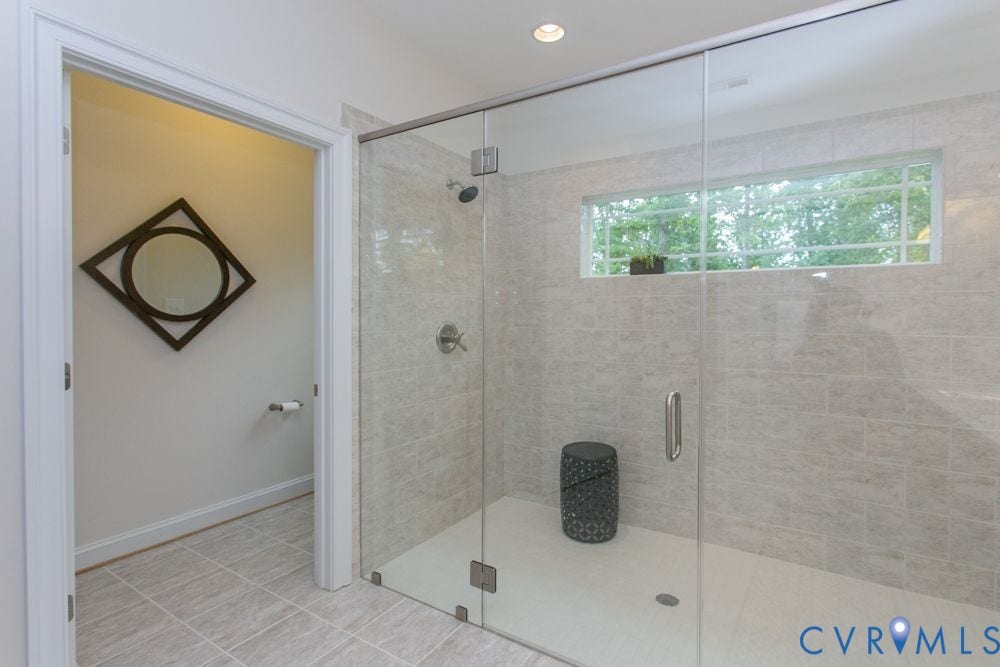 Glass-enclosed shower with tiled walls, a transom window, and a built-in shower head