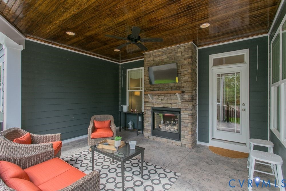 Covered patio featuring a wood-finish ceiling, stone-clad fireplace with mantel, ceiling fan, recessed lighting, and a glass-paneled door