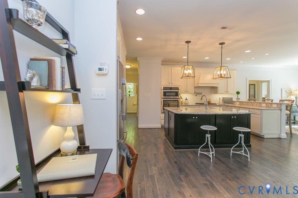 Hardwood flooring throughout, two-tone kitchen cabinetry, dual pendant lighting, recessed lighting, and stainless steel appliances