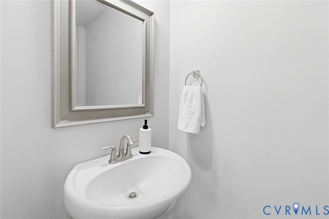 2002 Fairmount Avenue, Church Hill, Richmond, VA 23223 Wall-mounted pedestal sink with a brushed nickel faucet, framed mirror, and chrome towel ring