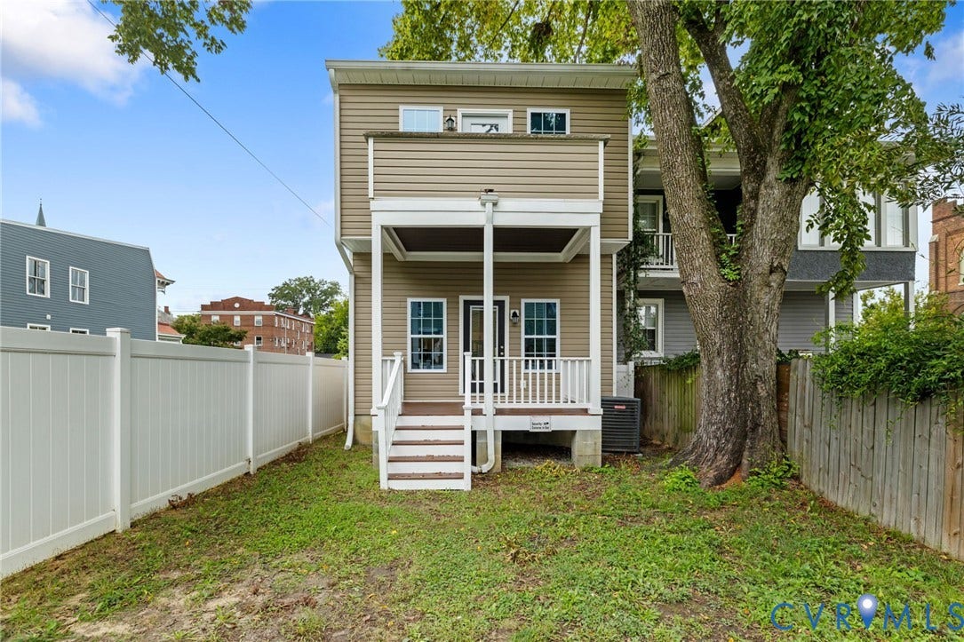 2002 Fairmount Avenue, Church Hill, Richmond, VA 23223 Two-story exterior with vinyl siding, covered lower patio, upper balcony, and a white privacy fence