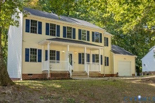 Two-story residence with a covered front porch, attached garage, and blue window shutters