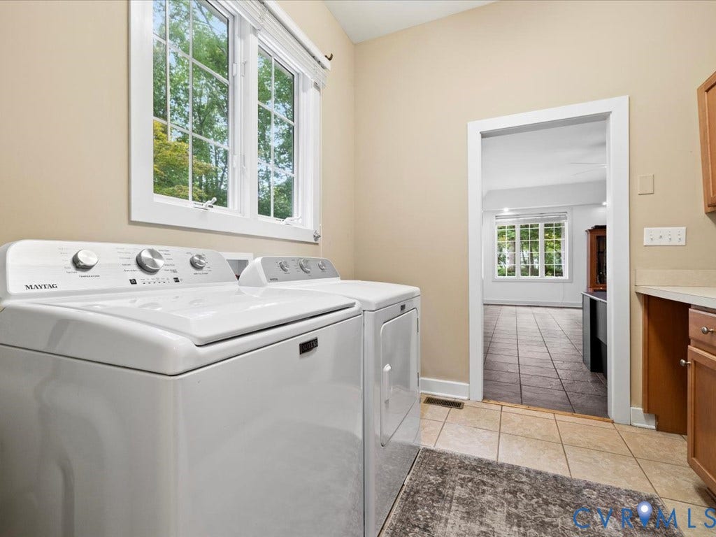 147 Oyster Cove Landing, Hartfield, VA 23071 Laundry area featuring tiled flooring, an exterior window, wood-finish cabinetry, and a countertop