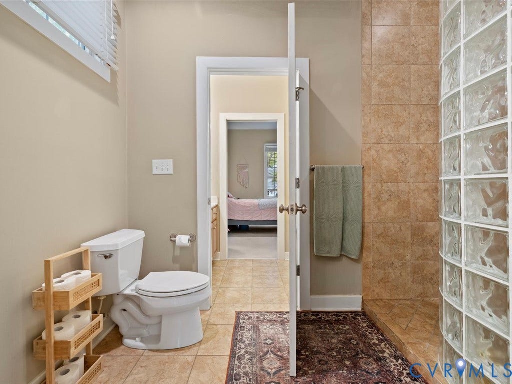 147 Oyster Cove Landing, Hartfield, VA 23071 Tiled bathroom flooring featuring a glass block shower enclosure and a built-in shower bench