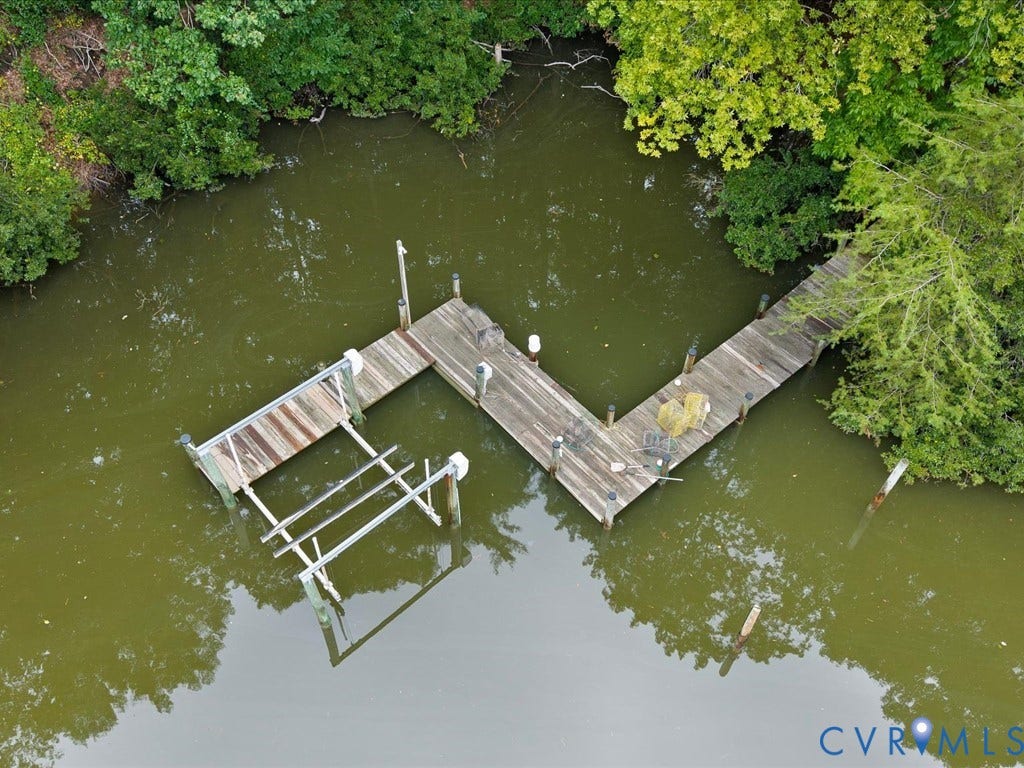147 Oyster Cove Landing, Hartfield, VA 23071 Wood dock extending over calm waters with surrounding lush foliage