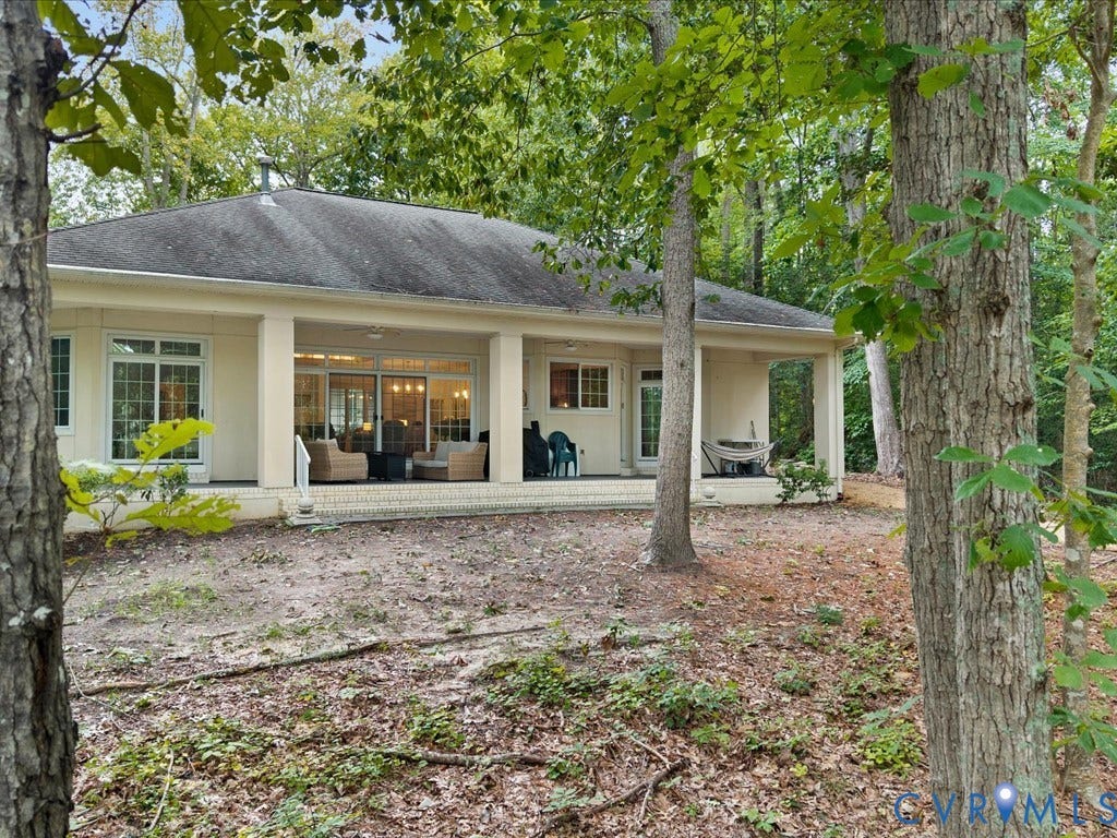 147 Oyster Cove Landing, Hartfield, VA 23071 Single-story exterior with a covered patio, multiple glass sliding doors, and mature trees surrounding the property
