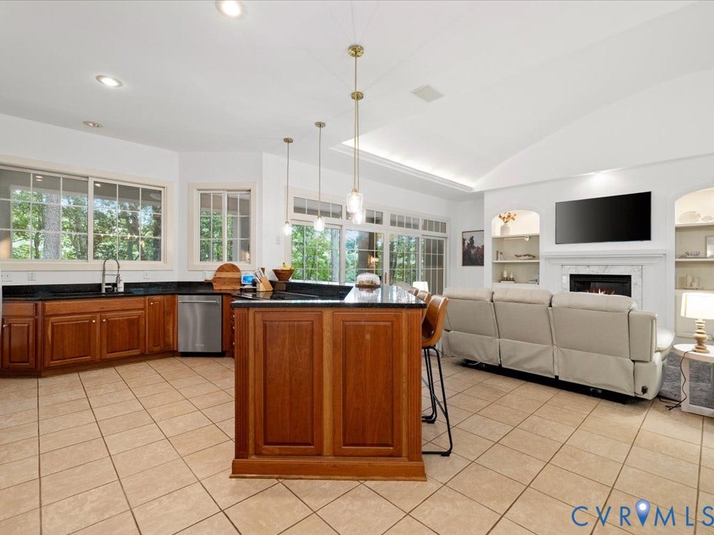 147 Oyster Cove Landing, Hartfield, VA 23071 Open-concept kitchen and living area featuring a central island with countertop seating, recessed lighting, and a fireplace with built-in shelving