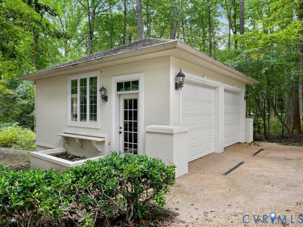 147 Oyster Cove Landing, Hartfield, VA 23071 Stucco exterior with two white garage doors, multi-pane windows, and a glass-paneled entry door
