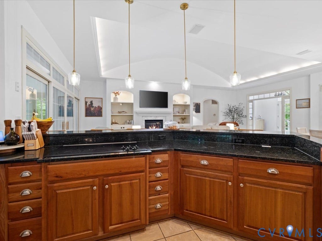 147 Oyster Cove Landing, Hartfield, VA 23071 Kitchen island with wood-finish cabinetry, black stone countertop, and integrated cooktop