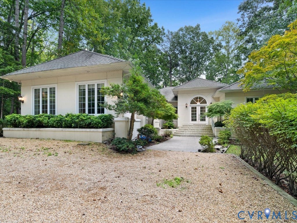 147 Oyster Cove Landing, Hartfield, VA 23071 Stucco exterior with multiple windows, arched double entry doors, and a gravel driveway