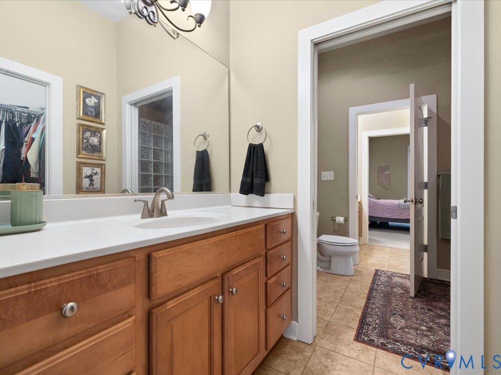 147 Oyster Cove Landing, Hartfield, VA 23071 Wood-finish vanity with white countertop, integrated sink, and brushed nickel faucet