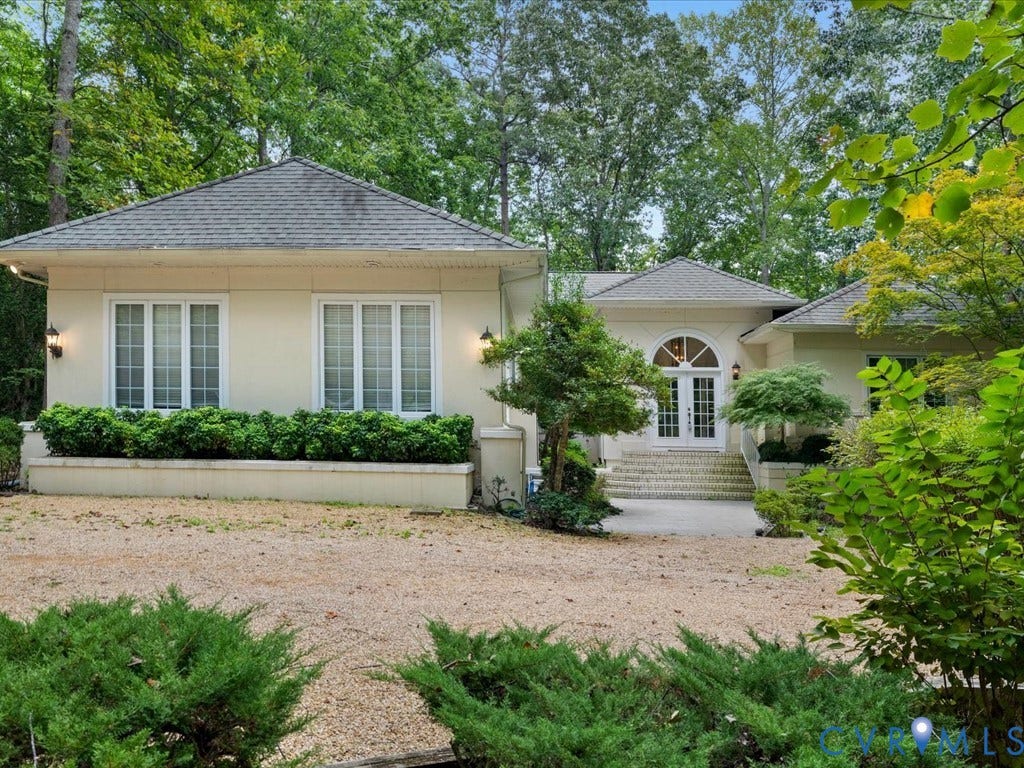 147 Oyster Cove Landing, Hartfield, VA 23071 Stucco exterior featuring multiple gabled roofs, arched double entry doors, exterior sconce lighting, and a gravel driveway