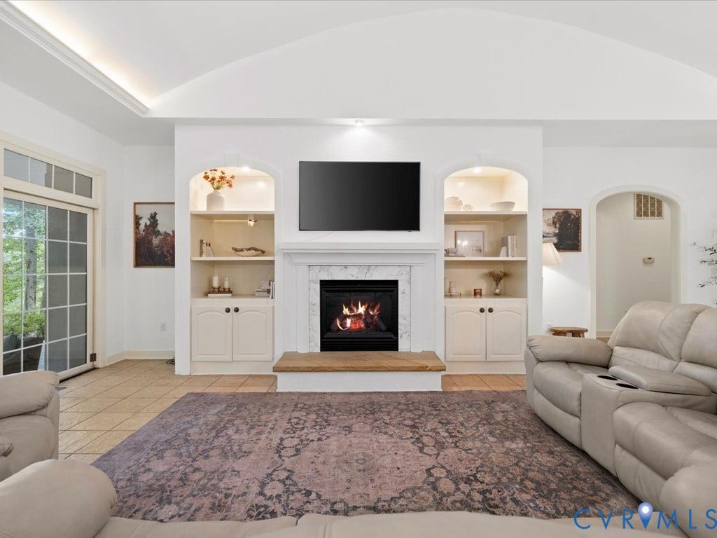 147 Oyster Cove Landing, Hartfield, VA 23071 Vaulted ceiling with crown molding, built-in shelving, fireplace with stone surround and hearth, and tiled flooring