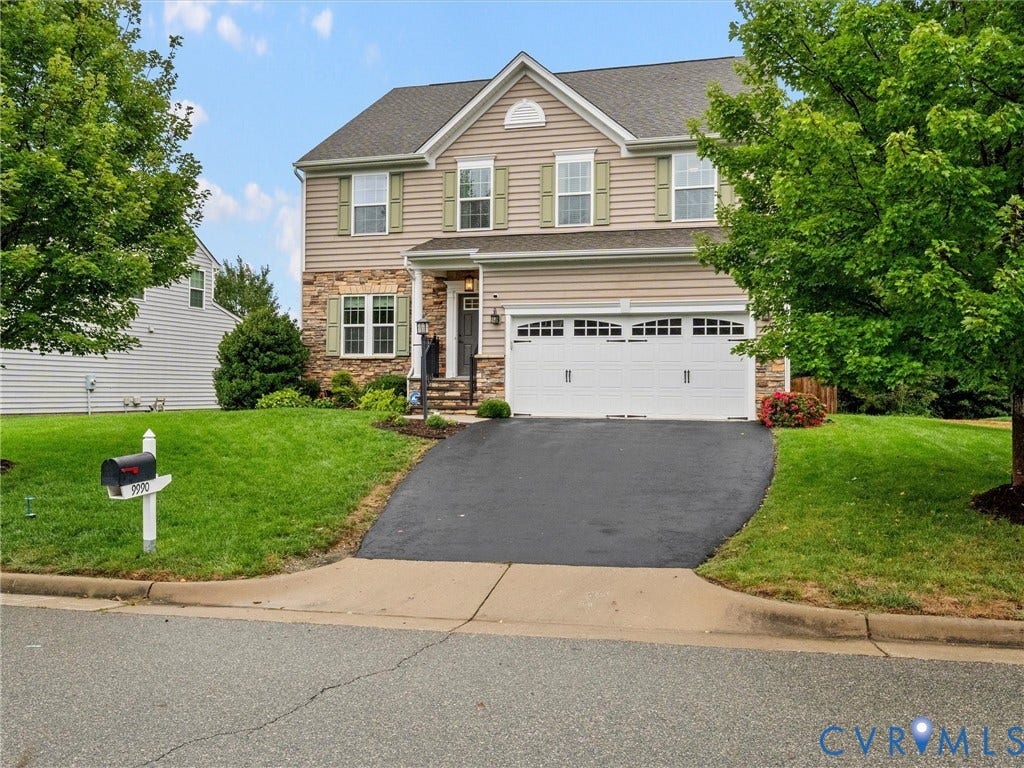 9990 Orchard Meadow Road, Mechanicsville, VA 23116 Two-story facade with stone and siding accents, prominent double garage, covered entry, and mature landscaping