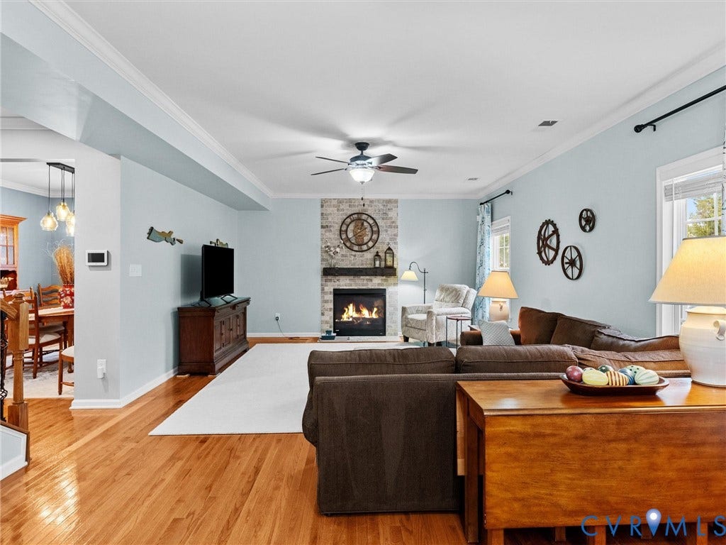 9990 Orchard Meadow Road, Mechanicsville, VA 23116 Hardwood flooring, crown molding, ceiling fan, and a fireplace with a stone surround