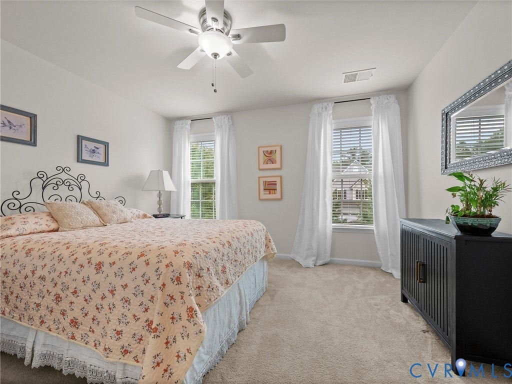 9990 Orchard Meadow Road, Mechanicsville, VA 23116 Light neutral wall paint, ceiling fan with integrated lighting, two windows with blinds, and neutral carpeting