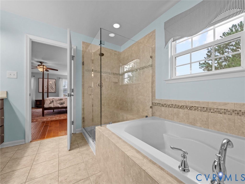 9990 Orchard Meadow Road, Mechanicsville, VA 23116 Tiled flooring, built-in soaking tub with deck-mounted faucet, glass-enclosed shower with tiled surround and recessed lighting, and a double-paned window