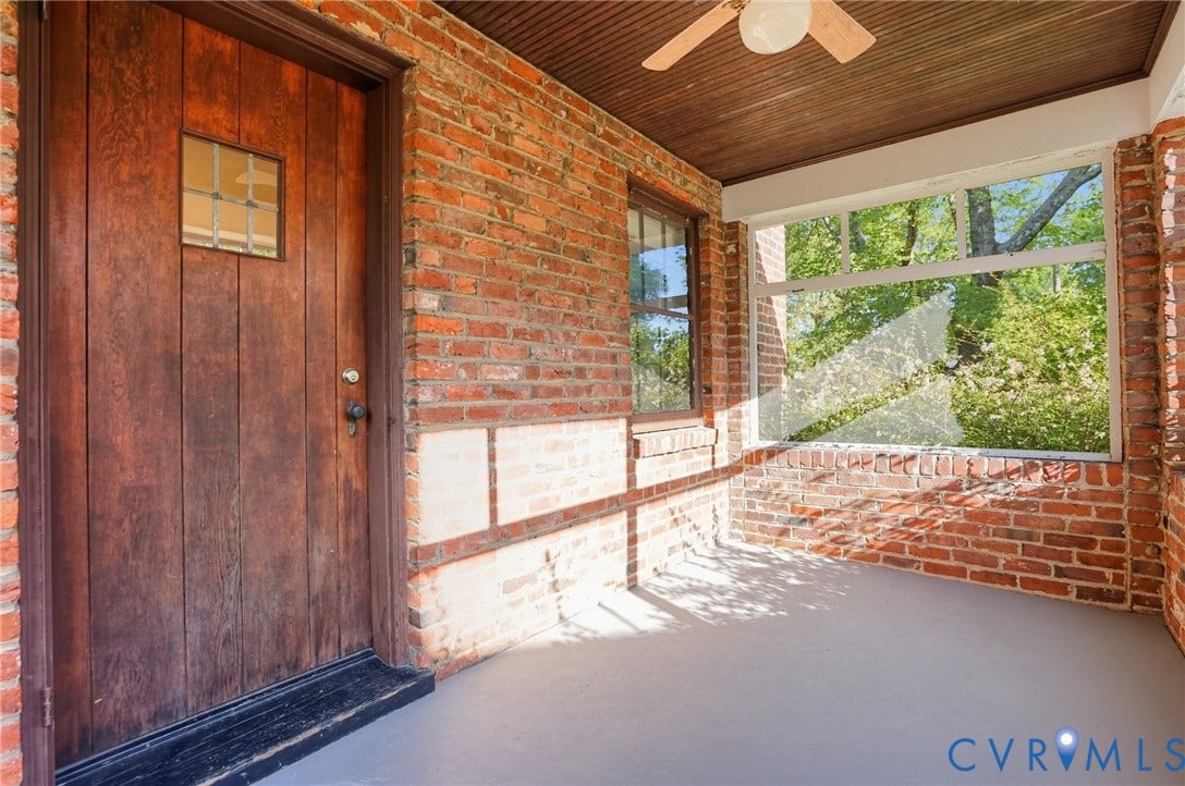 1713 Wilmington Avenue, Richmond, VA 23227 Covered porch featuring a paneled wood entry door with glass insert, brick walls, and a ceiling fan