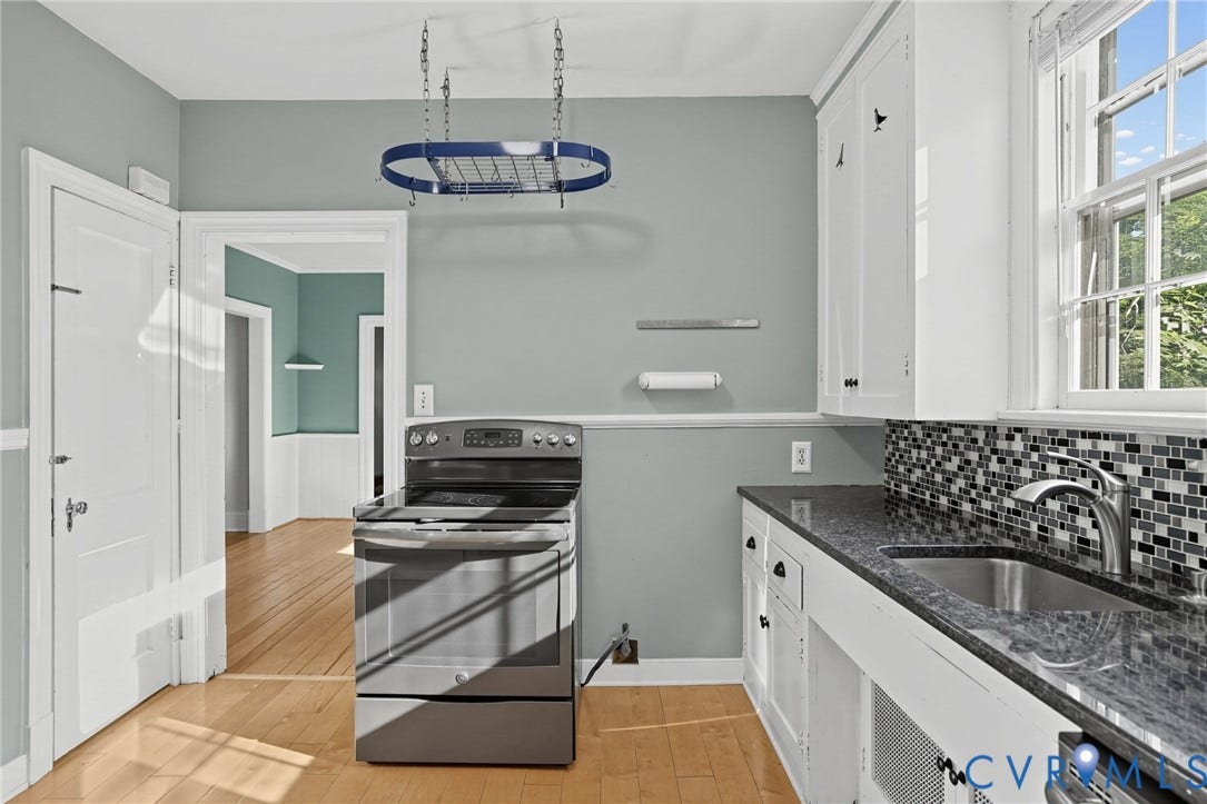 1713 Wilmington Avenue, Richmond, VA 23227 Kitchen featuring wood-finish flooring, white cabinetry, a stainless steel sink, and a multi-tone mosaic tile backsplash