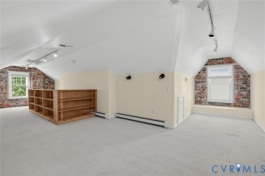 1713 Wilmington Avenue, Richmond, VA 23227 Spacious bonus room featuring exposed brick walls, track lighting, light-toned carpeting, and a built-in wooden bookcase