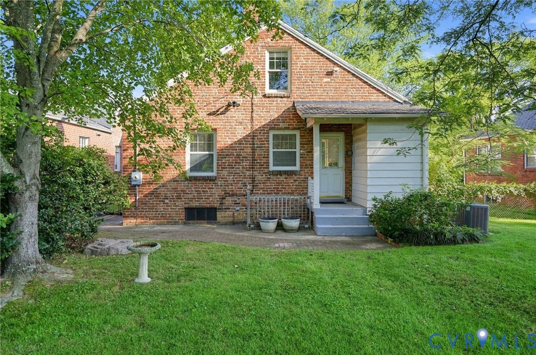 1713 Wilmington Avenue, Richmond, VA 23227 Brick exterior with a gabled roofline, concrete patio, and mature trees