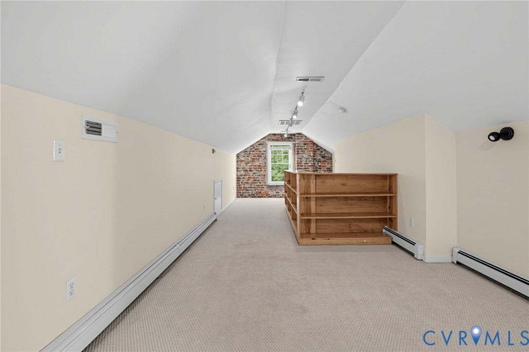 1713 Wilmington Avenue, Richmond, VA 23227 Carpeted attic space featuring sloped ceilings, track lighting, and a window with a brick wall surround