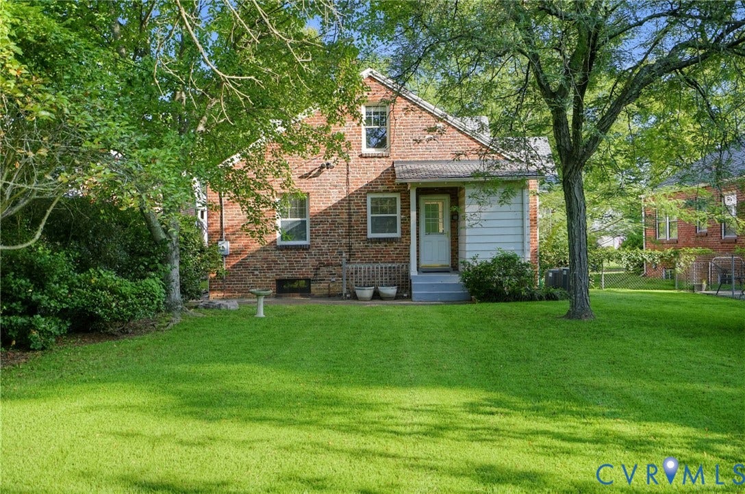 1713 Wilmington Avenue, Richmond, VA 23227 Brick exterior with a light blue door and white trim, featuring a manicured lawn and mature trees