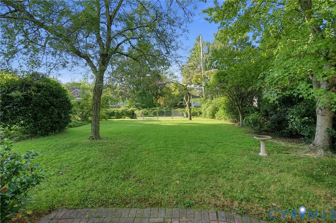 1713 Wilmington Avenue, Richmond, VA 23227 Expansive green lawn framed by mature trees and established shrubbery, featuring a decorative stone birdbath