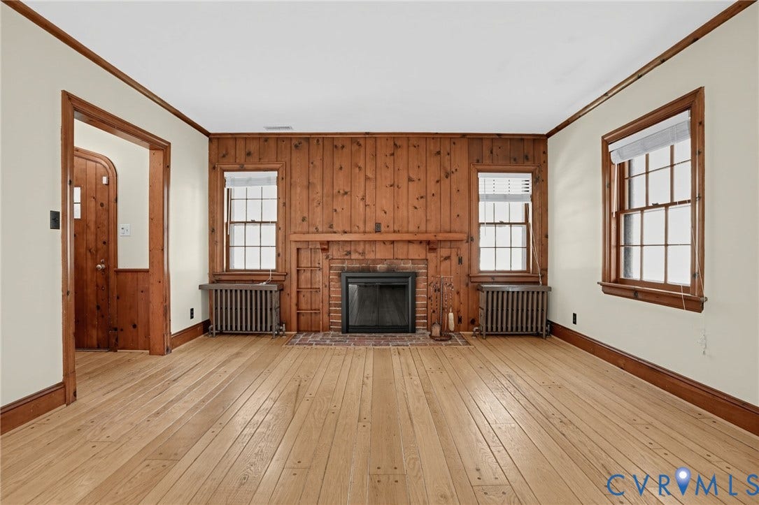 1713 Wilmington Avenue, Richmond, VA 23227 Hardwood flooring, wood-paneled accent wall, brick fireplace with mantel, and two windows