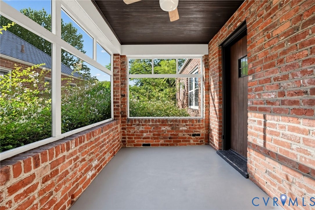 1713 Wilmington Avenue, Richmond, VA 23227 Brick enclosure featuring large windows, a dark wood-paneled door, and a painted concrete floor