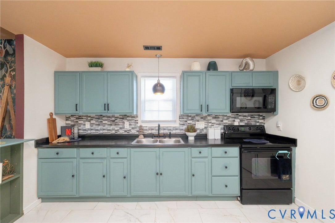 2127 Wright Avenue, Bellemeade, Richmond, VA 23224 Galley kitchen featuring soft blue cabinetry with ample storage, mosaic tile backsplash, black stainless steel appliances, black countertops, and pendant lighting above the sink