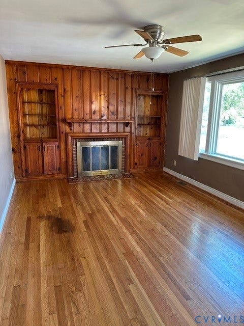 3311 Lanceor Drive, Henrico, VA 23060 Hardwood flooring, wood-paneled accent wall, built-in shelving, brick fireplace, and ceiling fan with integrated lighting