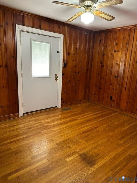 3311 Lanceor Drive, Henrico, VA 23060 Wood paneling, wood-finish flooring, white door with window pane, and a ceiling fan with integrated lighting