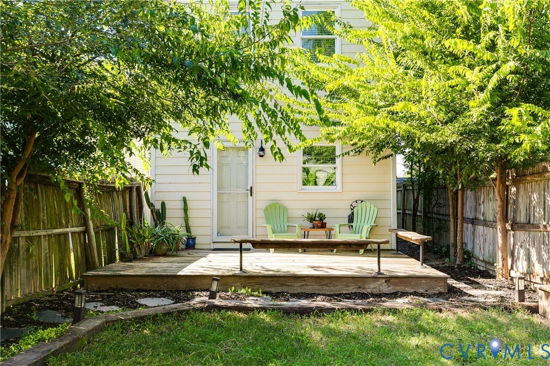 1311 N 33rd Street, Oakwood, Richmond, VA 23223 Rear exterior with a wood deck, mature trees, a privacy fence, and a green lawn