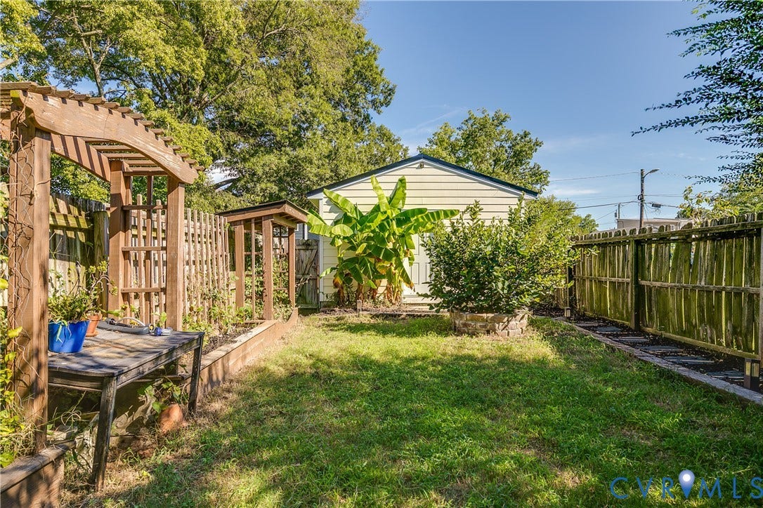 1311 N 33rd Street, Oakwood, Richmond, VA 23223 Expansive backyard featuring a wood pergola, raised garden beds, a detached shed, and mature perimeter fencing
