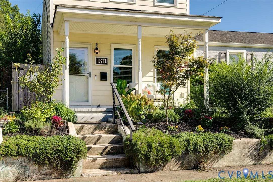 1311 N 33rd Street, Oakwood, Richmond, VA 23223 Inviting covered porch with white columns, concrete entry stairs, wrought iron railing, and established landscaping