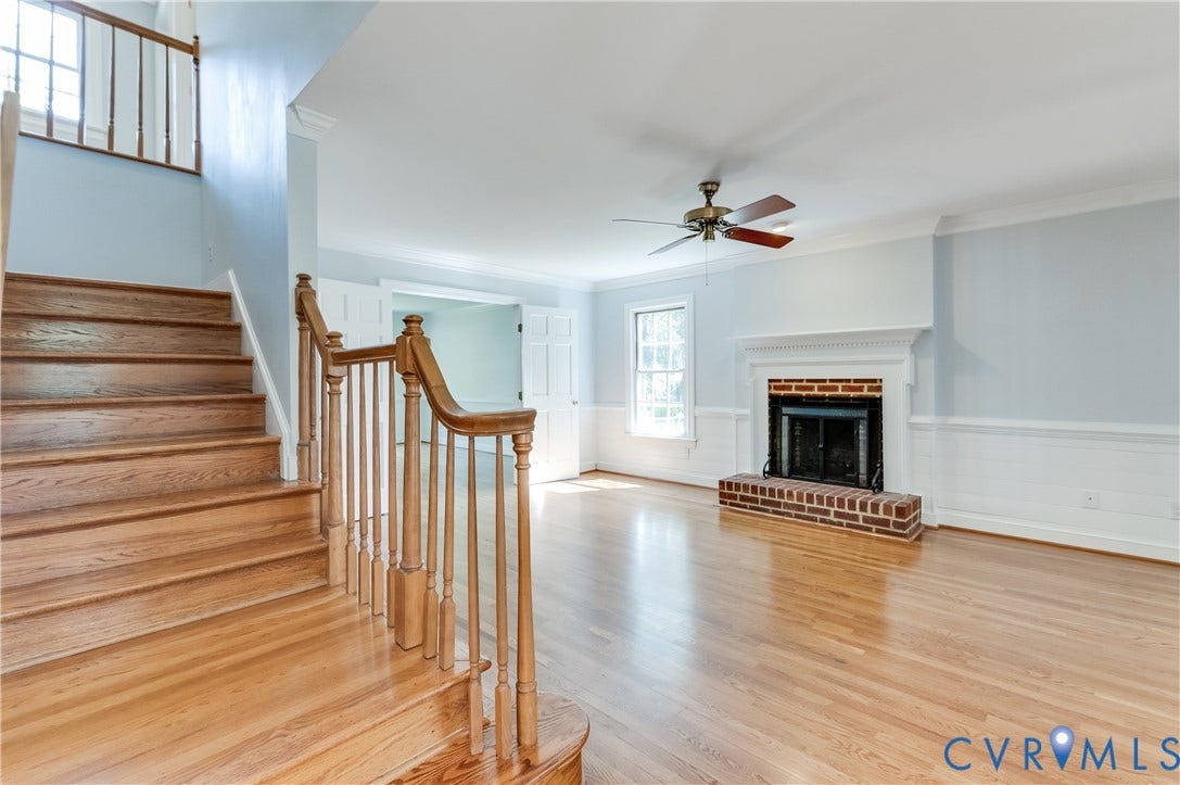11211 Warren View Road, Henrico, VA 23233 Hardwood flooring throughout, brick fireplace with white mantel, ceiling fan with light fixture, double-hung window, and a wood staircase with balusters