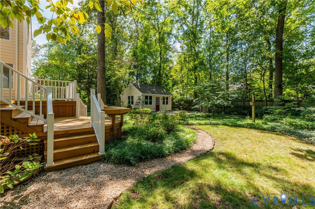 11211 Warren View Road, Henrico, VA 23233 Wood deck with white railings, gravel path, manicured lawn, lush trees, and a detached shed