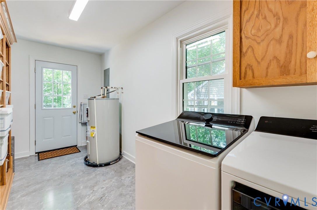 11211 Warren View Road, Henrico, VA 23233 Utility space featuring grey stone-finish flooring, a white paneled door with glass inserts, a single-hung window with white trim, and light wood-tone cabinetry