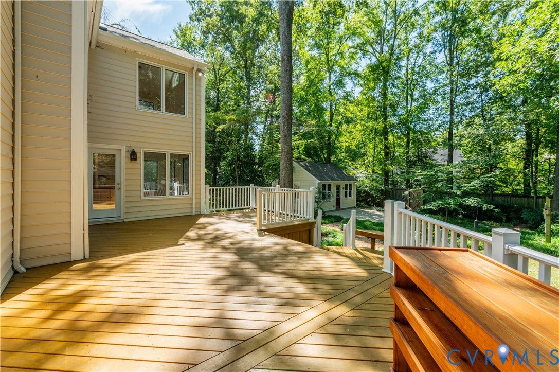 11211 Warren View Road, Henrico, VA 23233 Expansive wood deck with white railing, leading to a detached shed and lush tree coverage