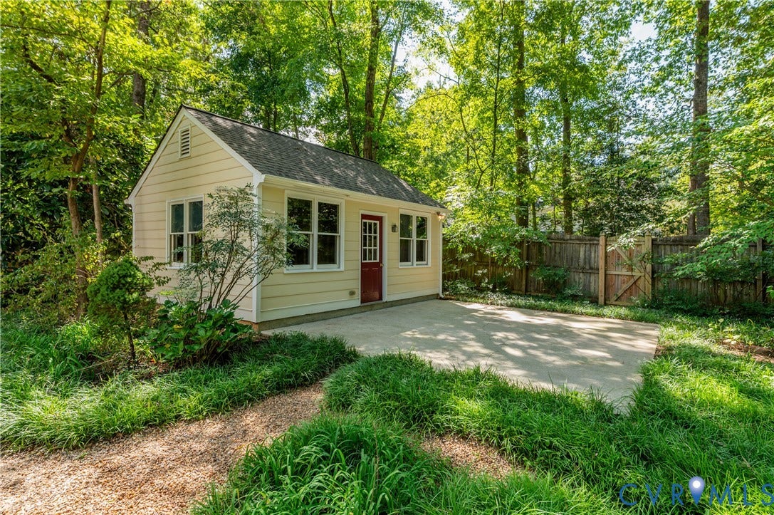 11211 Warren View Road, Henrico, VA 23233 Light yellow siding with white trim, a dark red paneled door, multiple windows, a concrete patio, and a gravel pathway