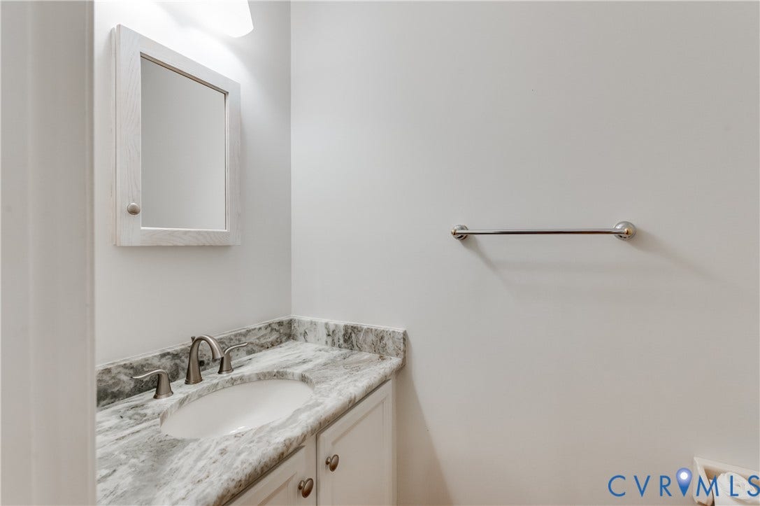 11211 Warren View Road, Henrico, VA 23233 White vanity with a neutral-toned stone countertop, undermount sink, and brushed nickel faucet