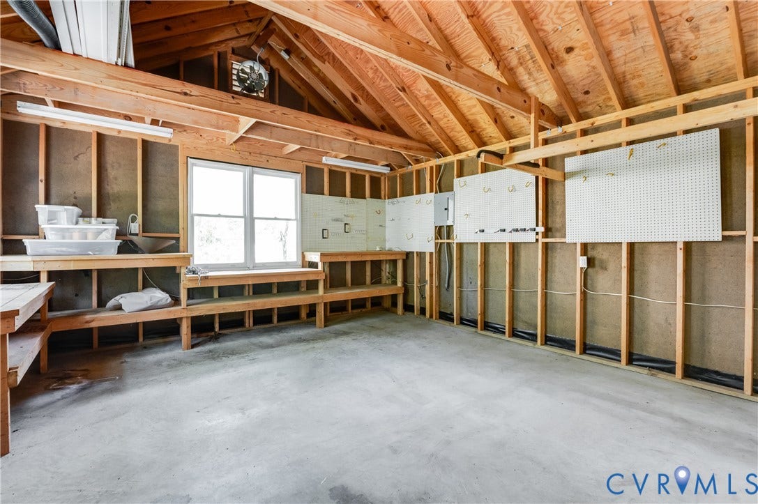 11211 Warren View Road, Henrico, VA 23233 Open-concept attic space featuring exposed wood framing, concrete flooring, built-in shelving, a double window, and fluorescent lighting
